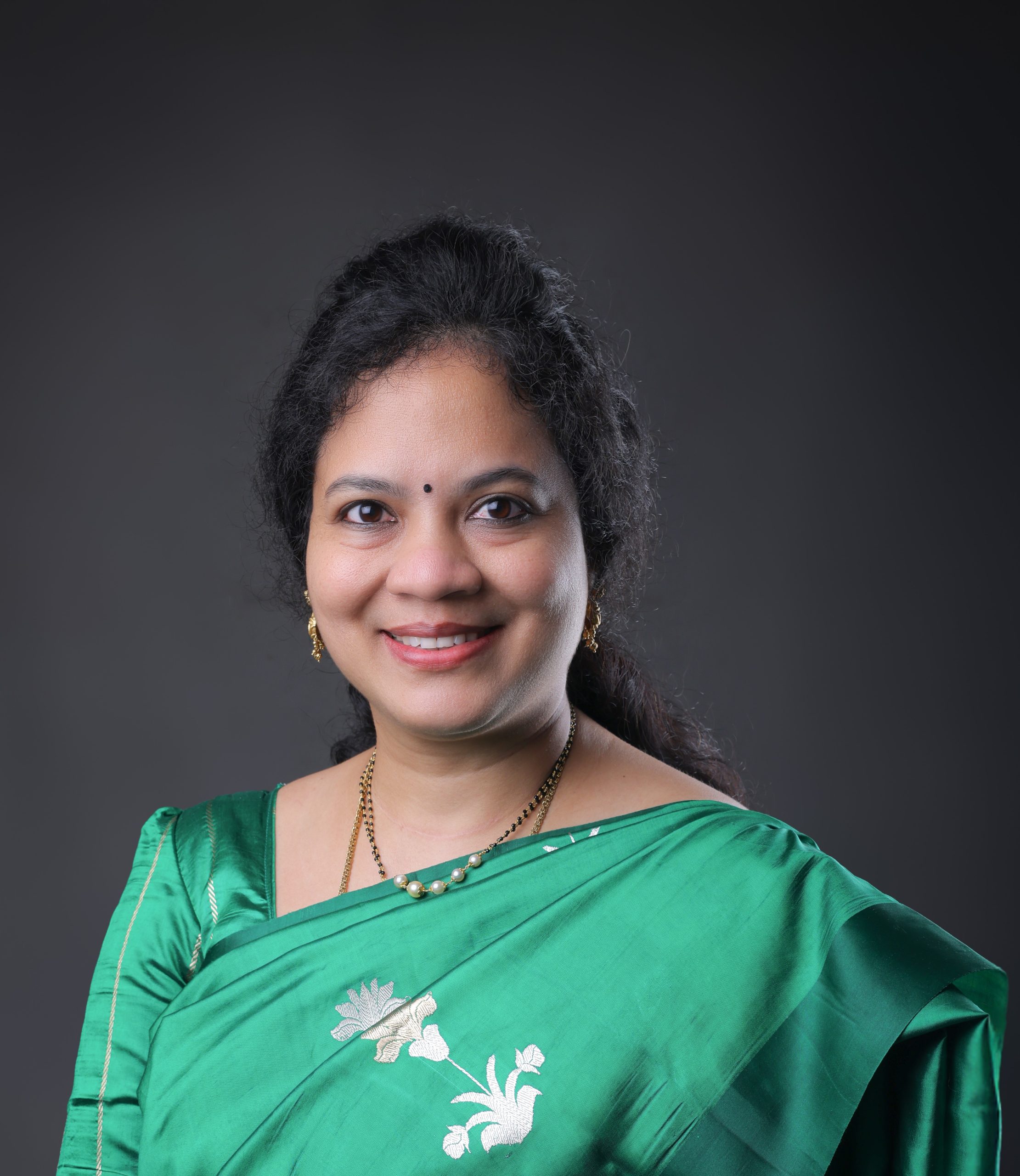 Professional Indian woman wearing a green saree, smiling portrait